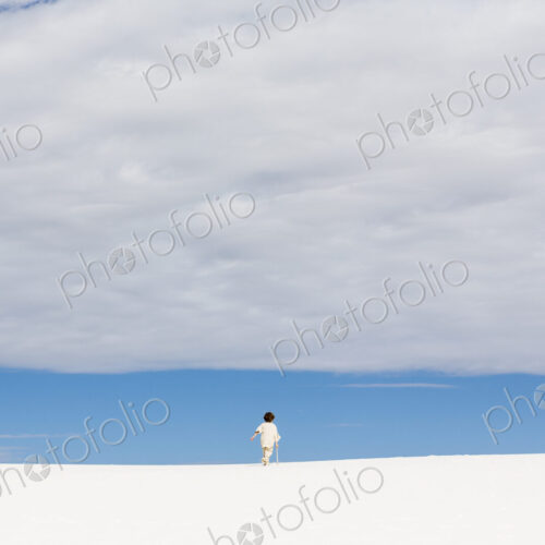 6 year old boy walking in white sand dunes, a strip of blue sky on the horizon and… 6 year old boy walking in white sand dunes, a strip of blue sky on the horizon and…