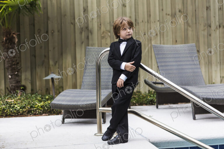 6 year old boy wearing formal attire standing by pool