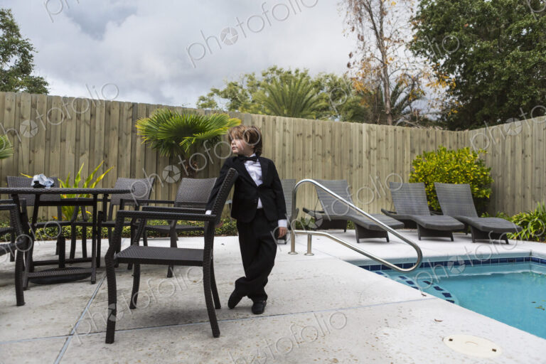 6 year old boy wearing formal attire standing by pool