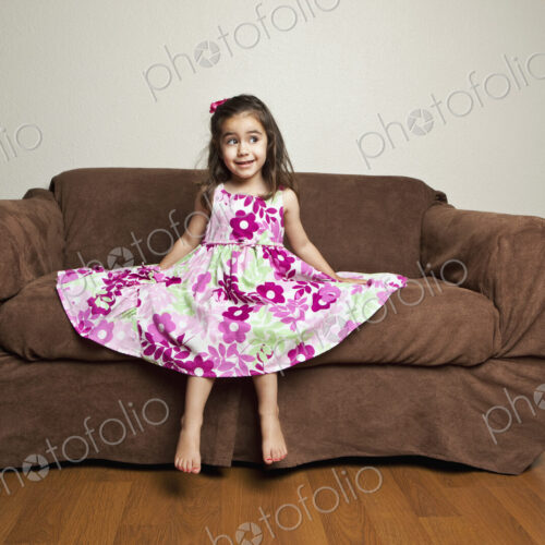 A 3 year old girl with long brown hair in a pink flowered cotton dress with the skirt…