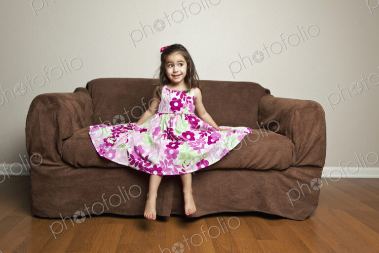 A 3 year old girl with long brown hair in a pink flowered cotton dress with the skirt…