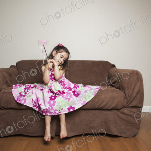 A 3 year old girl with long brown hair in a pink flowered cotton dress with the skirt…