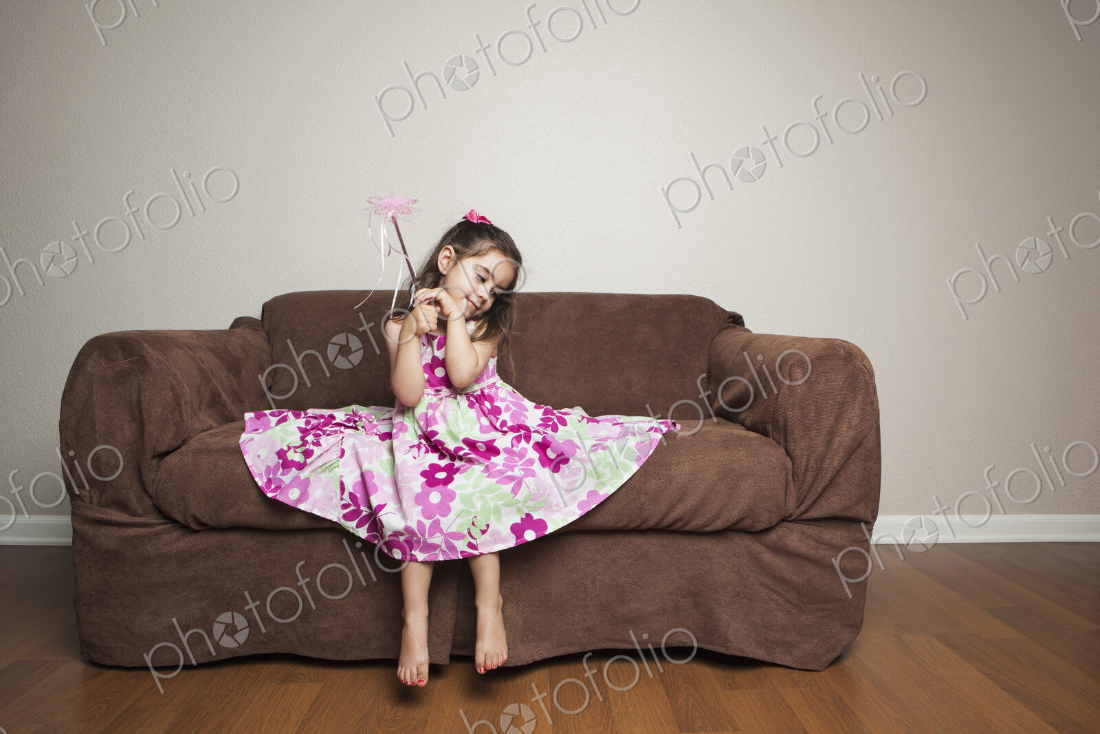 A 3 year old girl with long brown hair in a pink flowered cotton dress with the skirt…