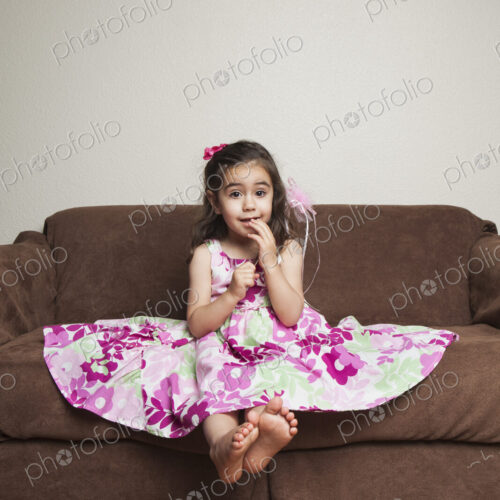 A 3 year old girl with long brown hair in a pink flowered cotton dress with the skirt…