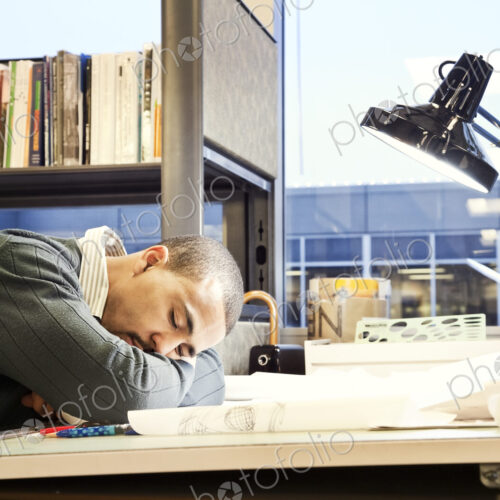 A Black man architect/designer taking a nap in his corporate office. A Black man architect/designer taking a nap in his corporate office.