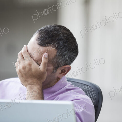 A Caucasian businessman pondering a problem while working on a laptop computer. A Caucasian businessman pondering a problem while working on a laptop computer.