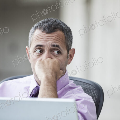 A Caucasian businessman pondering a problem while working on a laptop computer. A Caucasian businessman pondering a problem while working on a laptop computer.