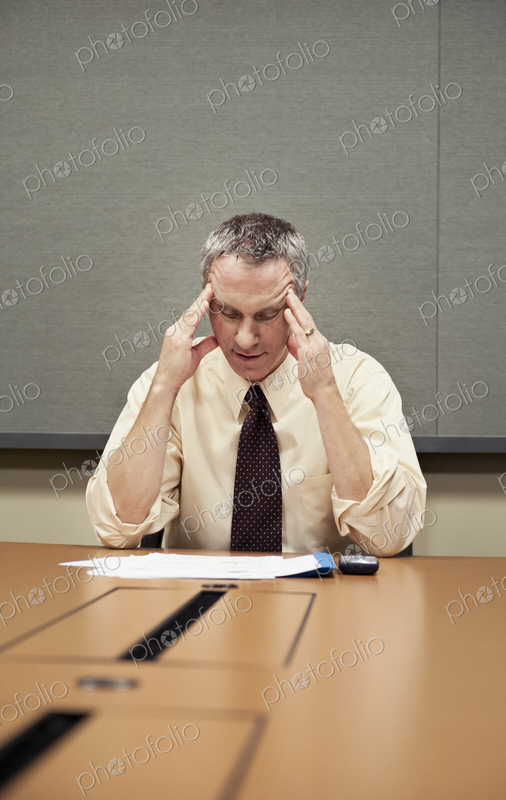A Caucasian businessman sitting at a desk showing the stress of work.