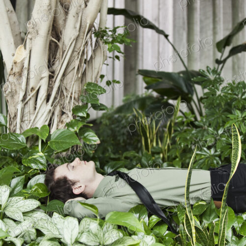 A Caucasian businessman taking a break in a convention center lobby full of indoor plants. A Caucasian businessman taking a break in a convention center lobby full of indoor plants.