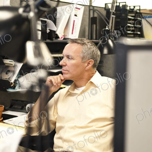 A Caucasian businessman working at his desk in a corporate office.