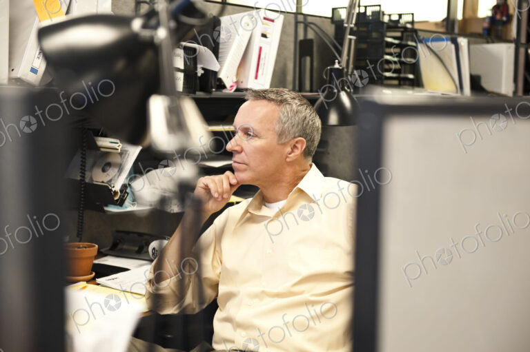 A Caucasian businessman working at his desk in a corporate office.