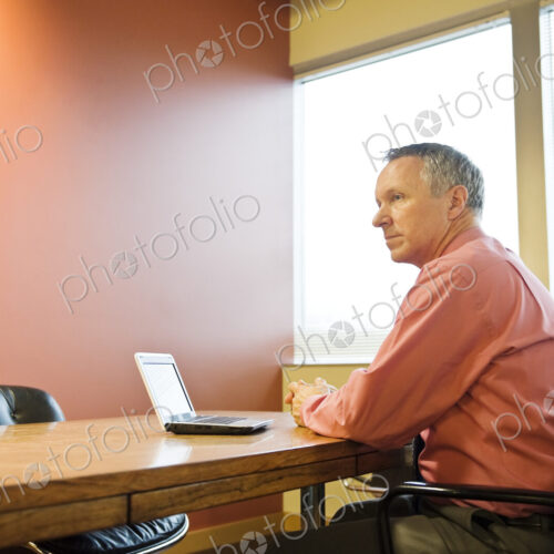 A Caucasian businessman working at his desk in a corporate office.