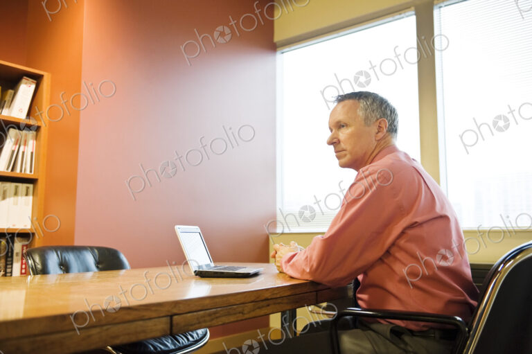 A Caucasian businessman working at his desk in a corporate office.