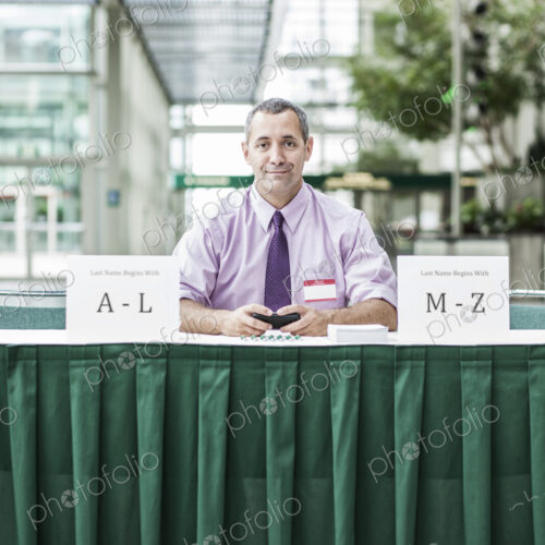 A Caucasian businessman working at registration desk in a convention center. A Caucasian businessman working at registration desk in a convention center.