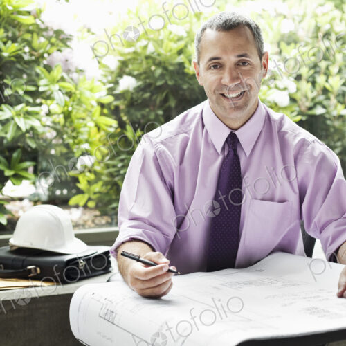 A Caucasian businessman working on architectural plans in his office. A Caucasian businessman working on architectural plans in his office.