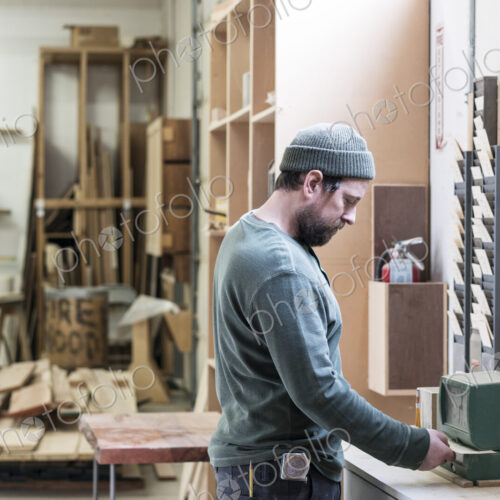 A Caucasian carpenter checking in with a time clock in a woodworking factory. A Caucasian carpenter checking in with a time clock in a woodworking factory.