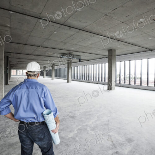A Caucasian male architect standing looking out over a new raw business space. A Caucasian male architect standing looking out over a new raw business space.