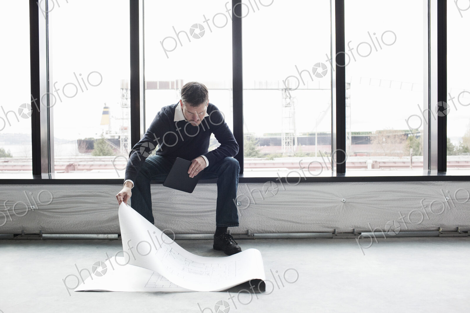 A Caucasian male architect working on building plans in a new raw business space.