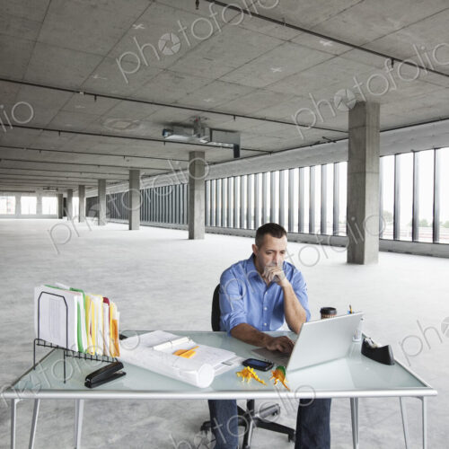 A Caucasian male business owner at his temporary desk in a new raw business space. A Caucasian male business owner at his temporary desk in a new raw business space.