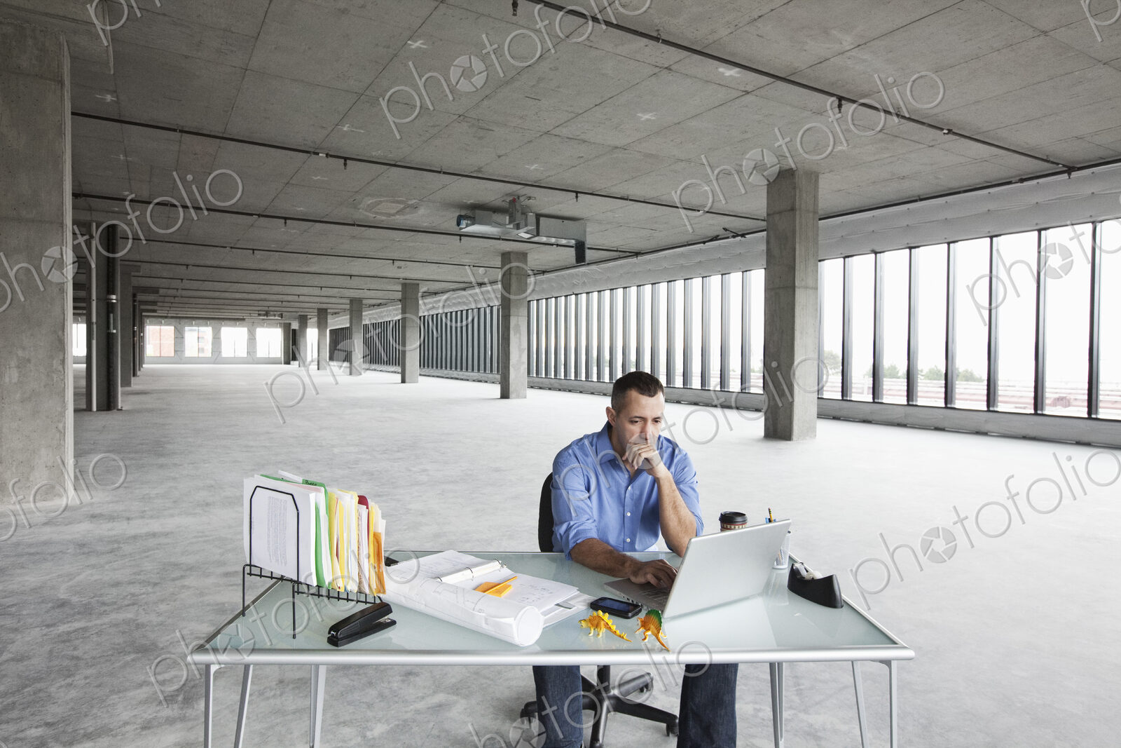 A Caucasian male business owner at his temporary desk in a new raw business space.