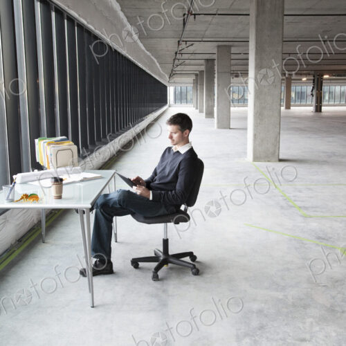 A Caucasian male business owner at his temporary desk in a new raw business space. A Caucasian male business owner at his temporary desk in a new raw business space.