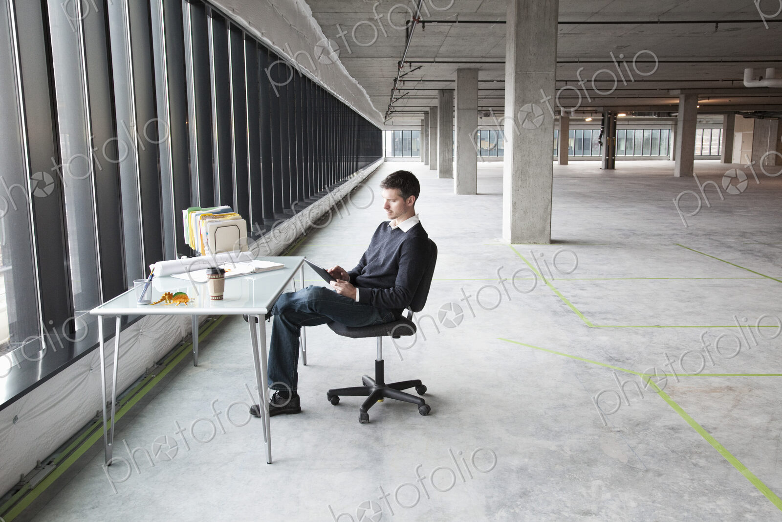 A Caucasian male business owner at his temporary desk in a new raw business space.