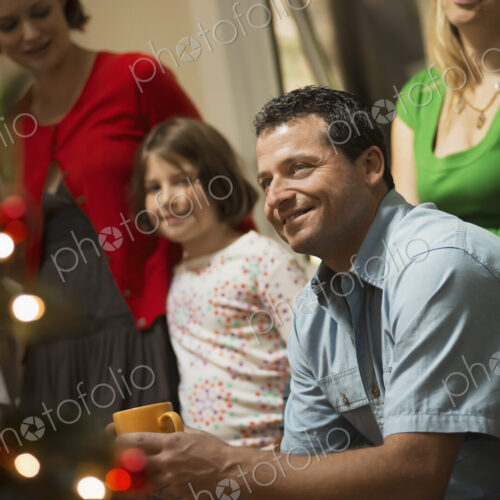 A Christmas gathering, adults and children in a room around a Christmas tree,… A Christmas gathering, adults and children in a room around a Christmas tree,…