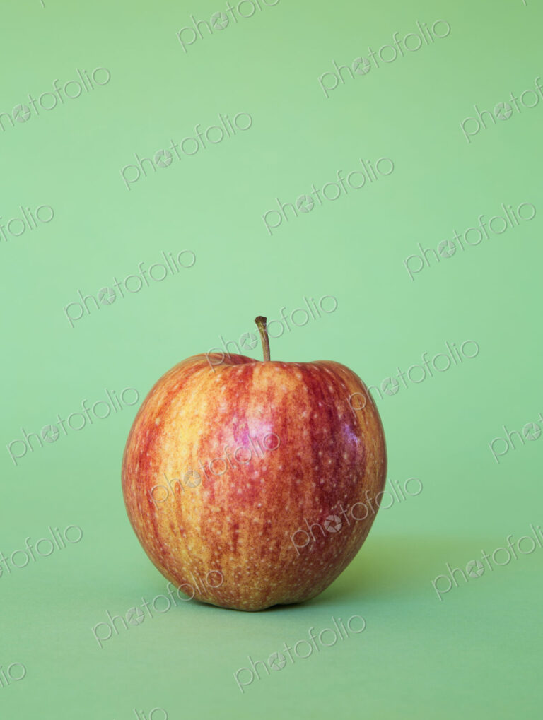 A Honey Crisp apple on a green background