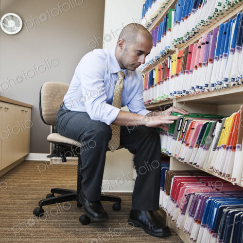 A Middle Eastern businessman looking through file folders, searching through paperwork… A Middle Eastern businessman looking through file folders, searching through paperwork…
