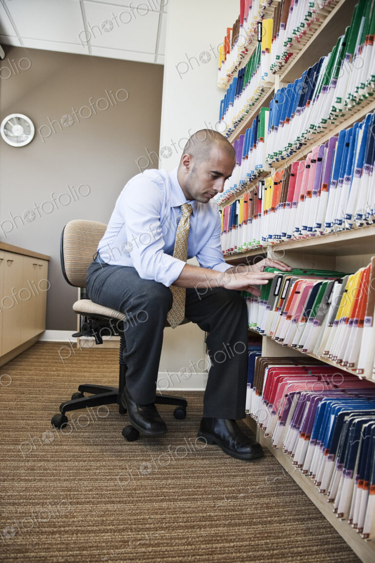 A Middle Eastern businessman looking through file folders, searching through paperwork…