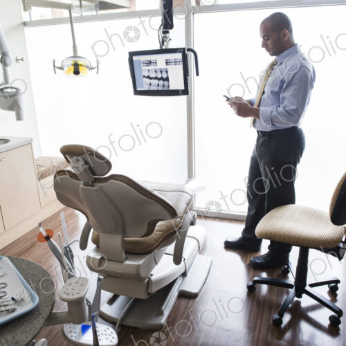 A Middle Eastern male dentist checking his cell phone in a dental examination room