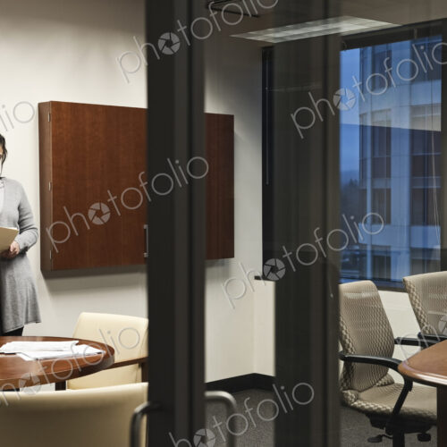 A Mixed Race woman working in an office, viewed through a glass doorway. A Mixed Race woman working in an office, viewed through a glass doorway.