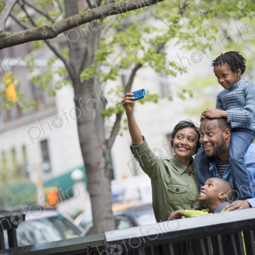 A New York city park in the spring. A boy riding on his father's shoulders, and a… A New York city park in the spring. A boy riding on his father's shoulders, and a…