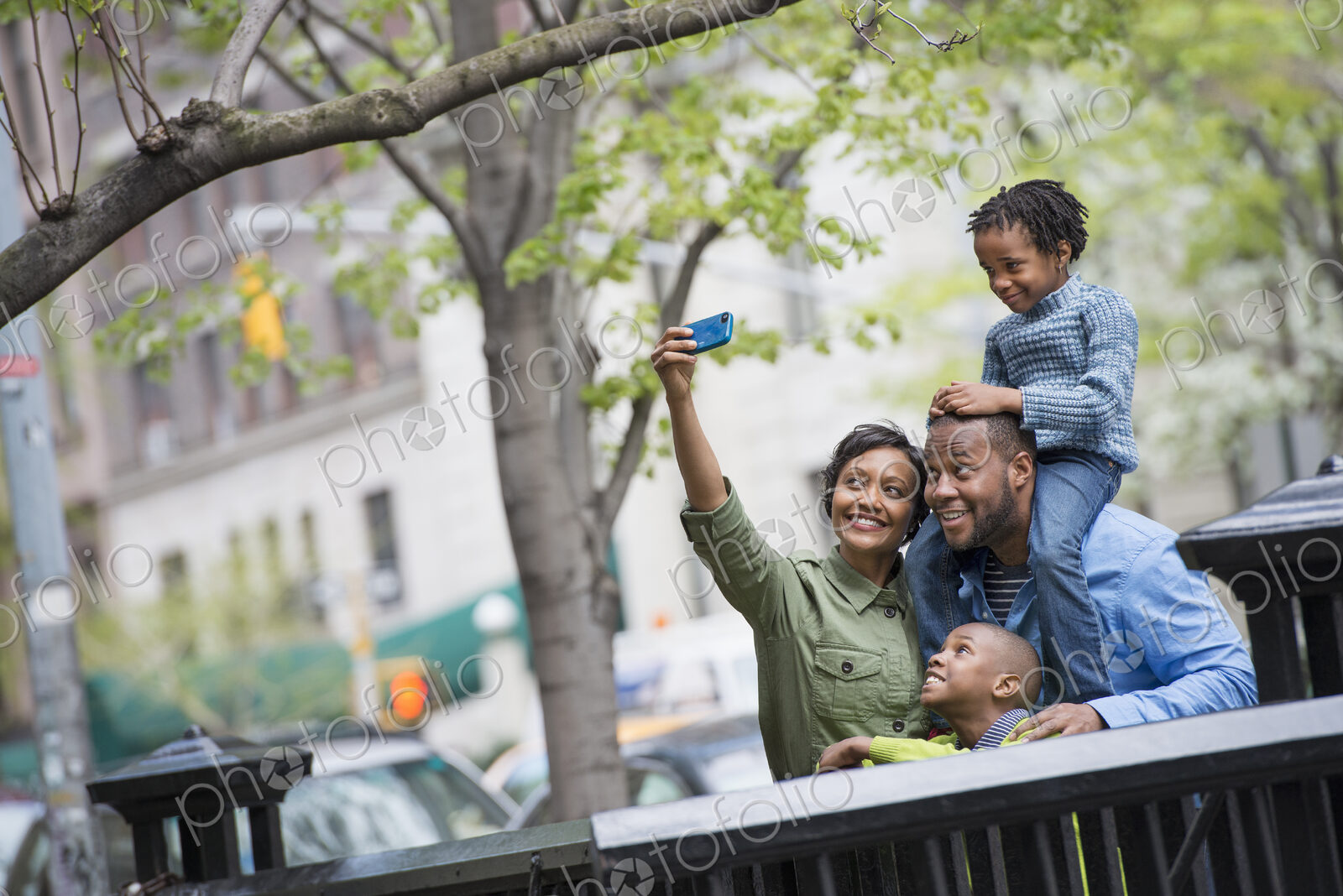 A New York city park in the spring. A boy riding on his father’s shoulders, and a…