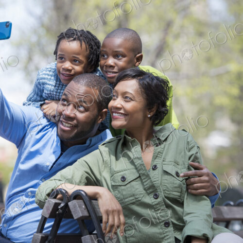 A New York city park in the spring. A family, parents and two boys taking a photograph… A New York city park in the spring. A family, parents and two boys taking a photograph…