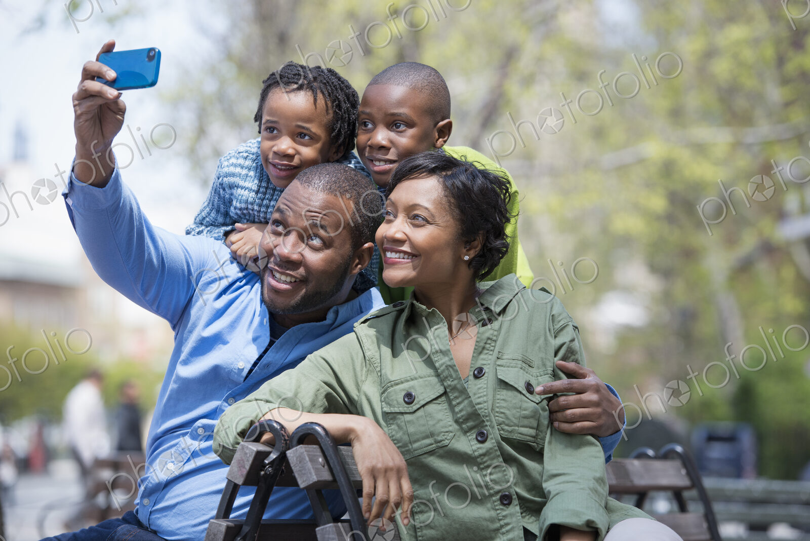 A New York city park in the spring. A family, parents and two boys taking a photograph…