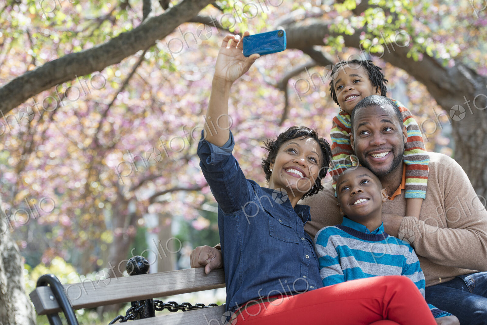 A New York city park in the spring. Cherry blossom. A woman taking a selfy picture…