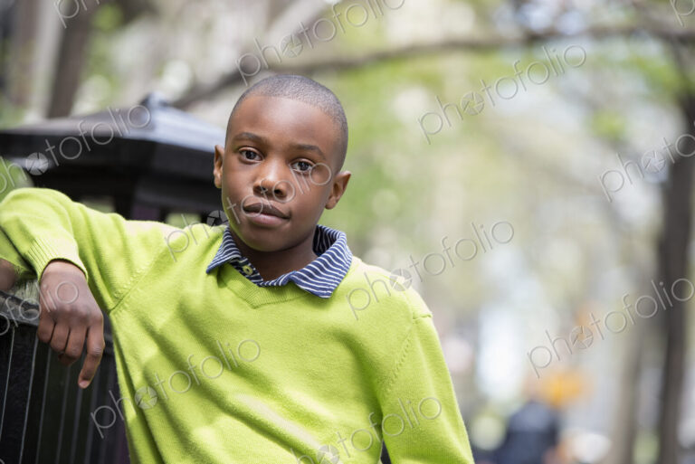 A New York city park in the spring. Sunshine and cherry blossom. A boy in a green…