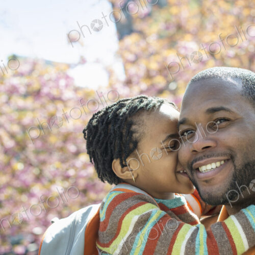 A New York city park in the spring. Sunshine and cherry blossom. A father and son in…