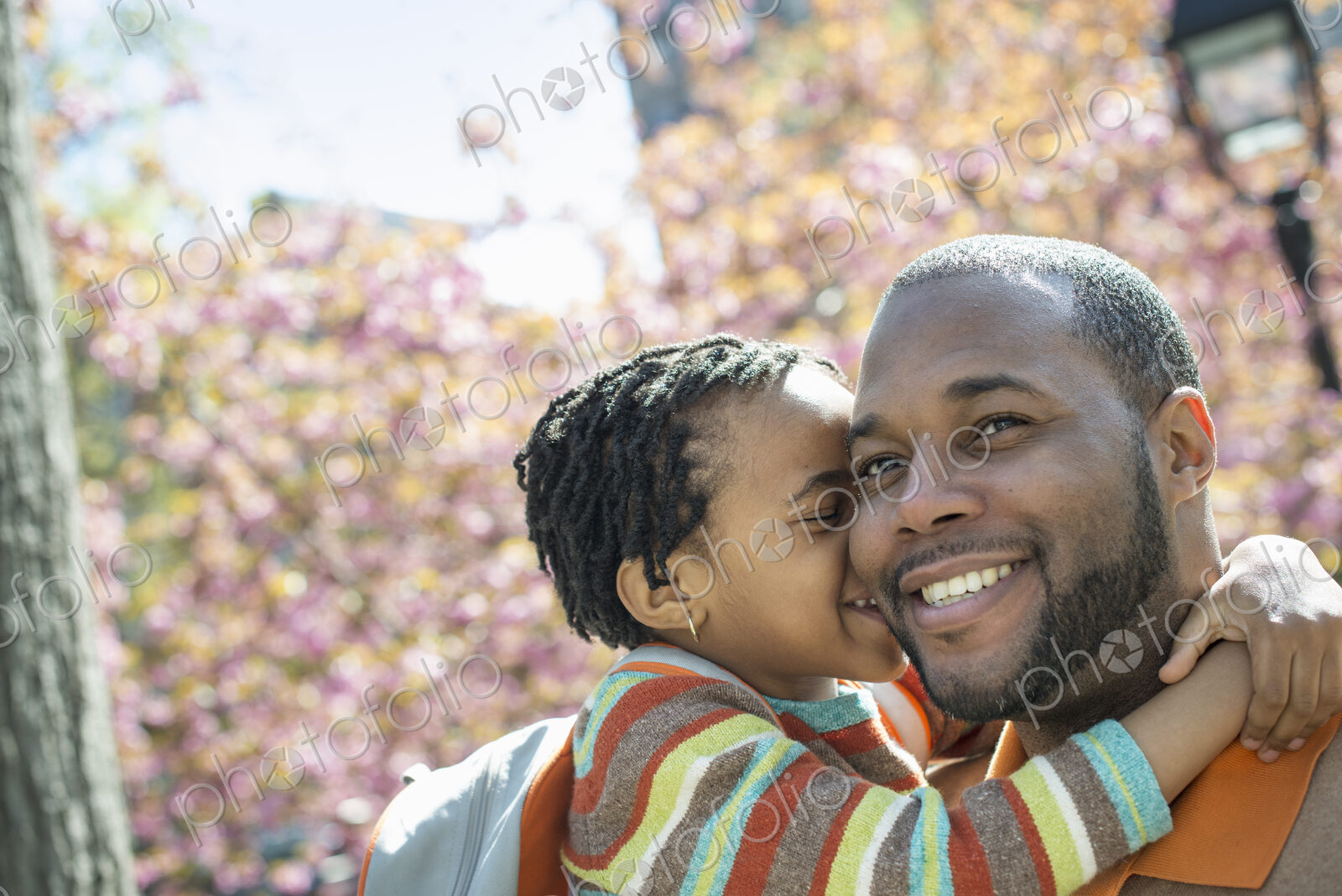 A New York city park in the spring. Sunshine and cherry blossom. A father and son in…