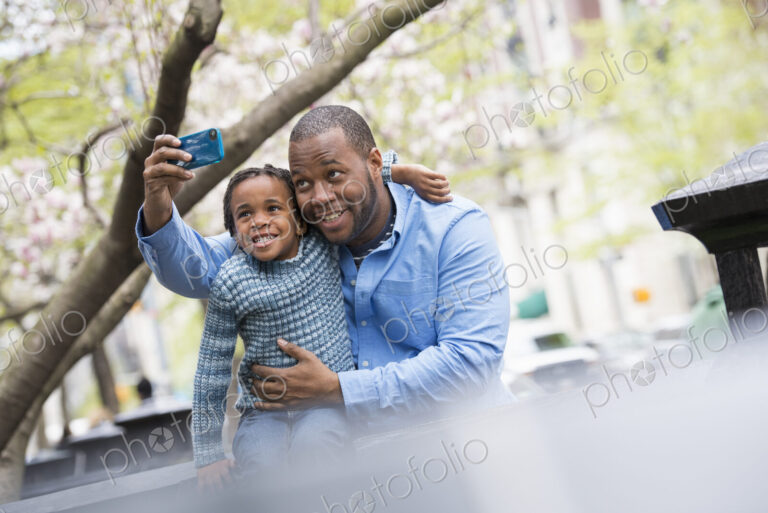 A New York city park in the spring. Sunshine and cherry blossom. A father and son side…
