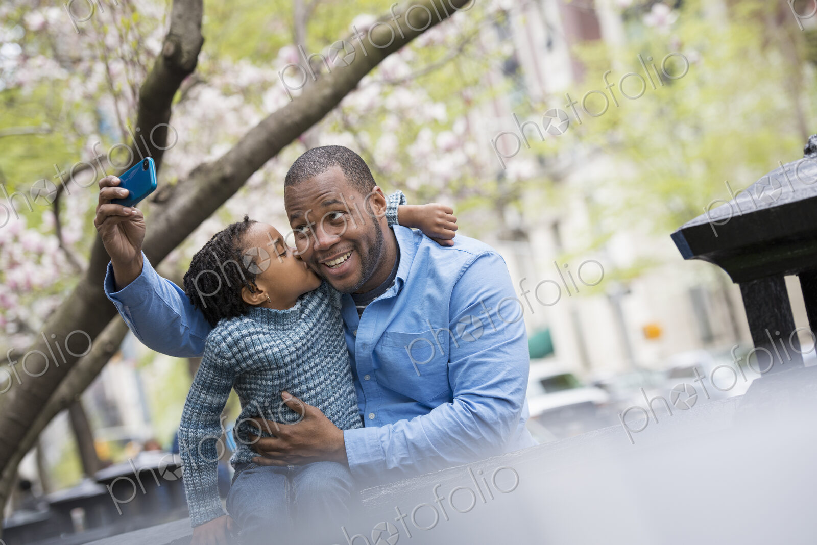 A New York city park in the spring. Sunshine and cherry blossom. A father and son side…