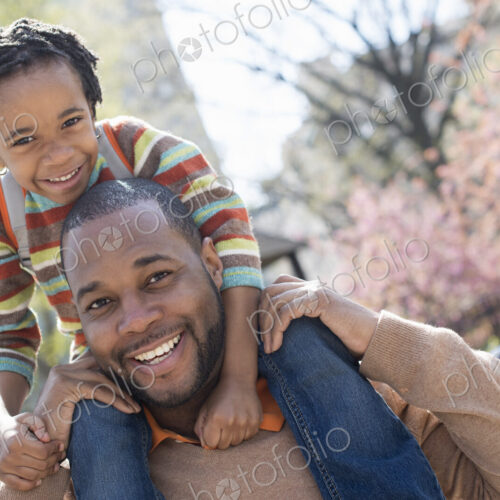 A New York city park in the spring. Sunshine and cherry blossom. A father carrying his…
