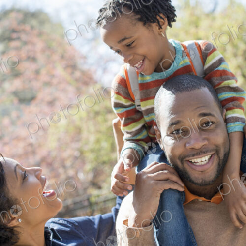A New York city park in the spring. Sunshine and cherry blossom. A father carrying his…