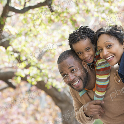A New York city park in the spring. Sunshine and cherry blossom. A father carrying his…