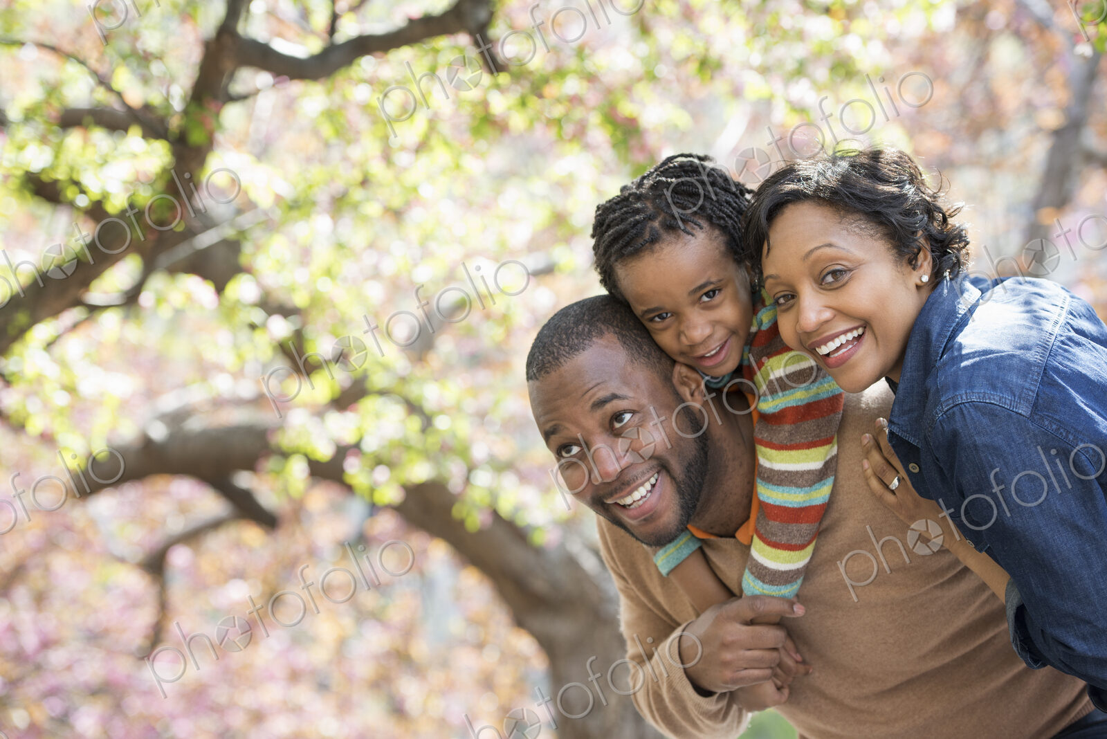 A New York city park in the spring. Sunshine and cherry blossom. A father carrying his…