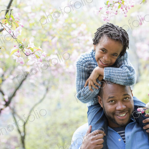 A New York city park in the spring. Sunshine and cherry blossom. A father giving his…