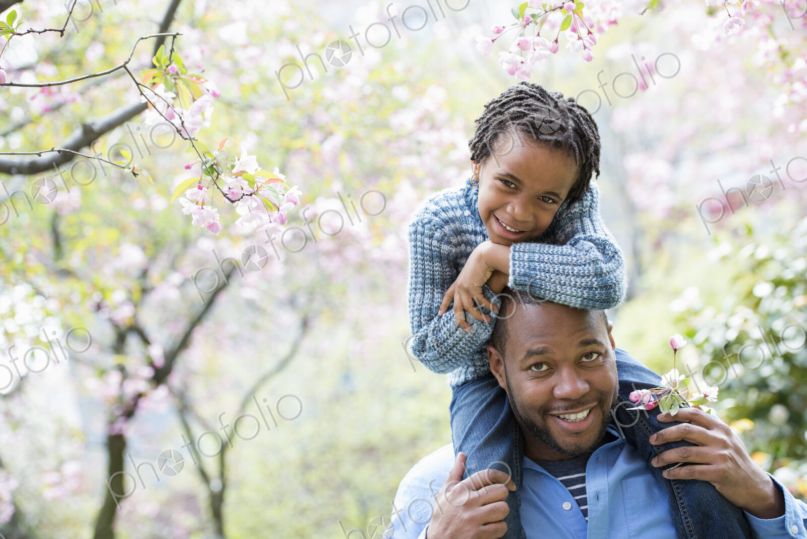A New York city park in the spring. Sunshine and cherry blossom. A father giving his…