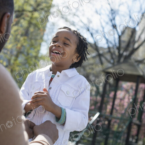 A New York city park in the spring. Sunshine and cherry blossom. A father kneeling and…
