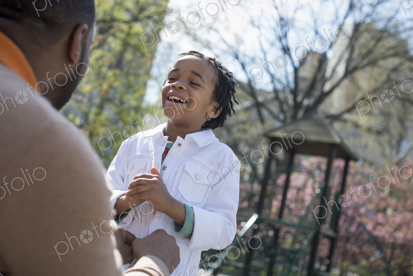 A New York city park in the spring. Sunshine and cherry blossom. A father kneeling and…